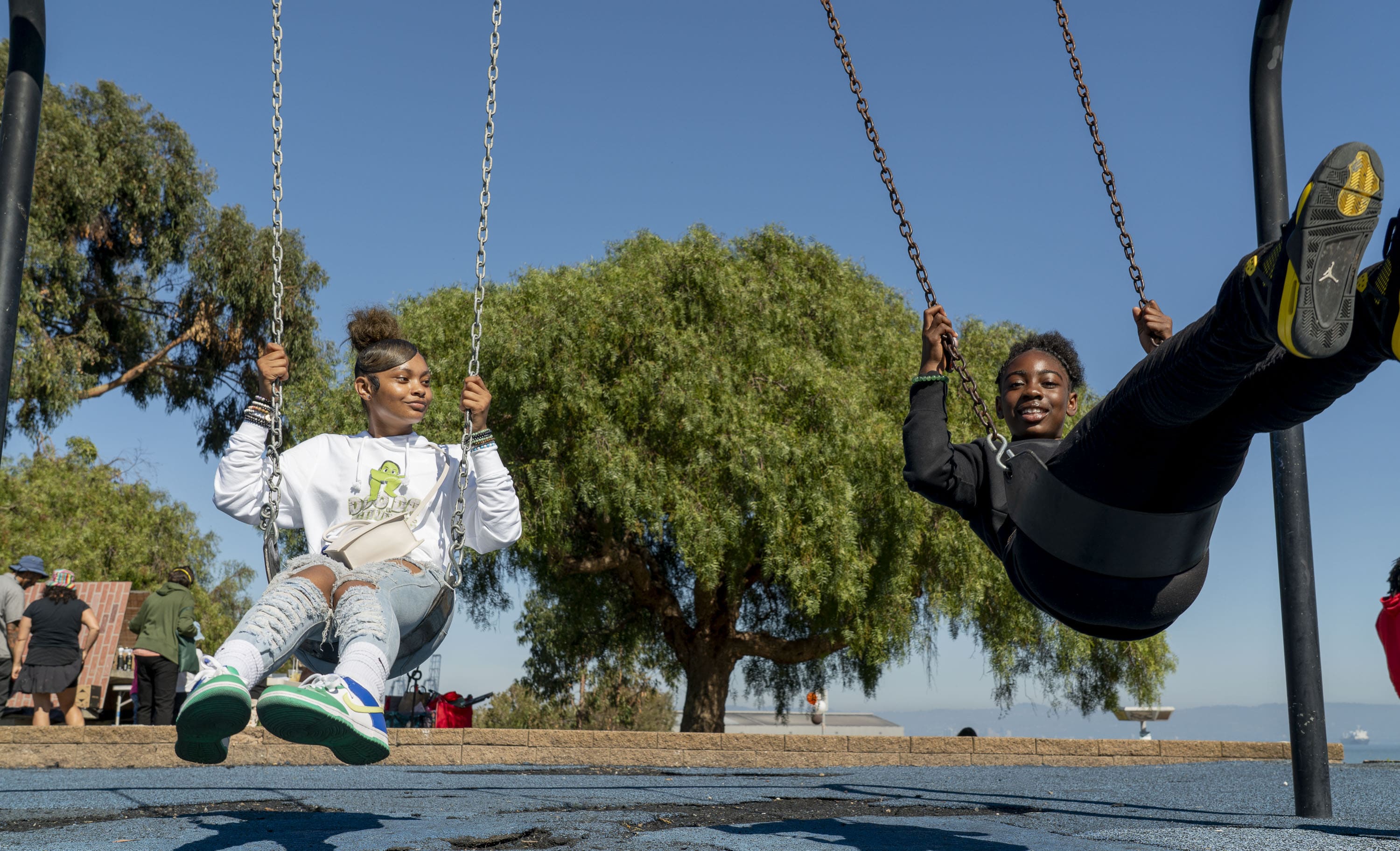 Two teenagers swinging in a park