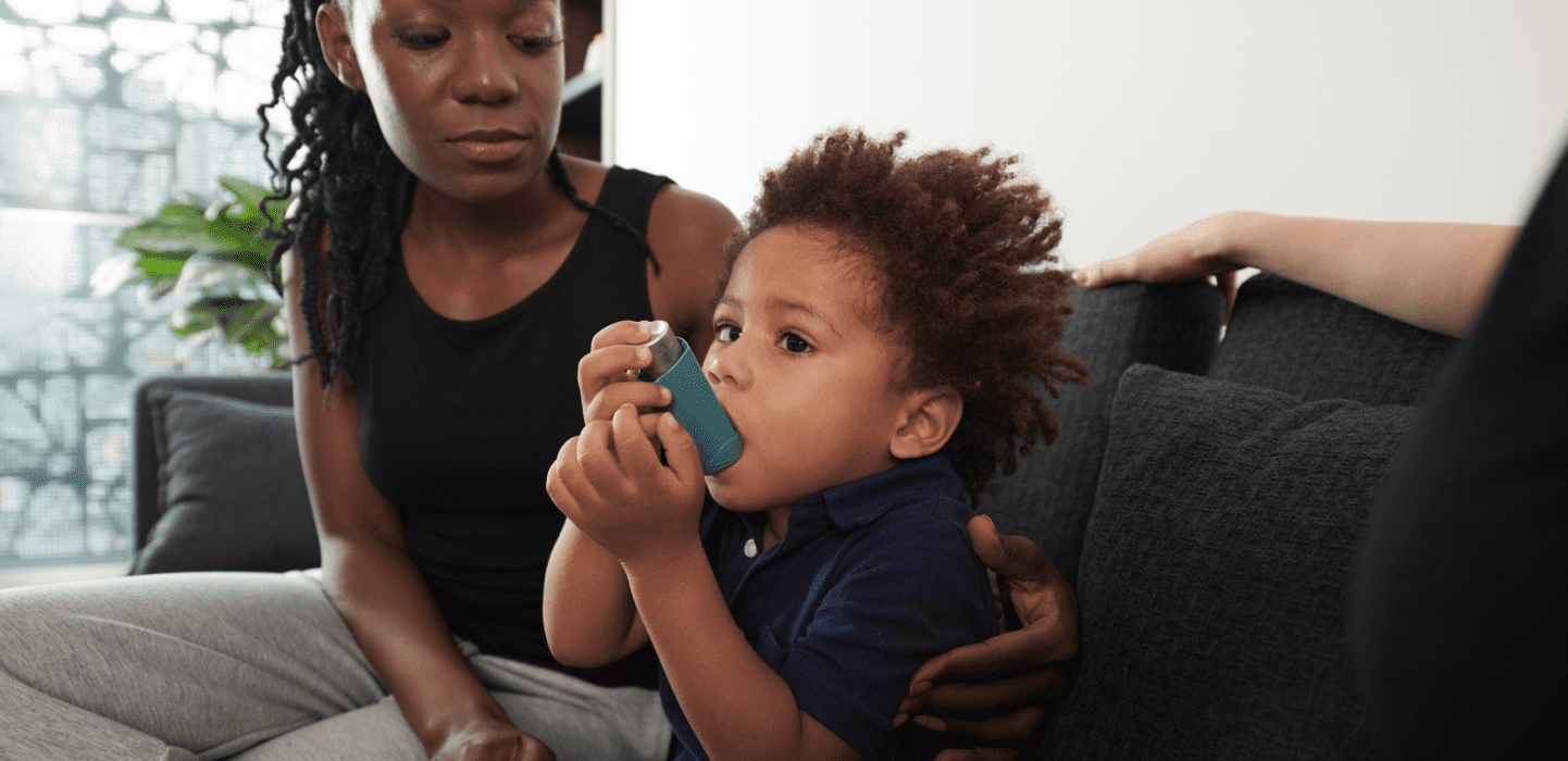 Mother sitting beside toddler using an inhaler