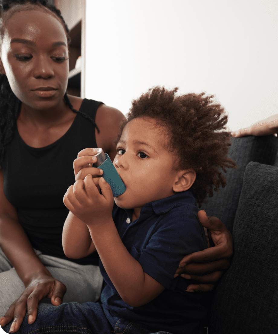 Mother sitting beside toddler using an inhaler